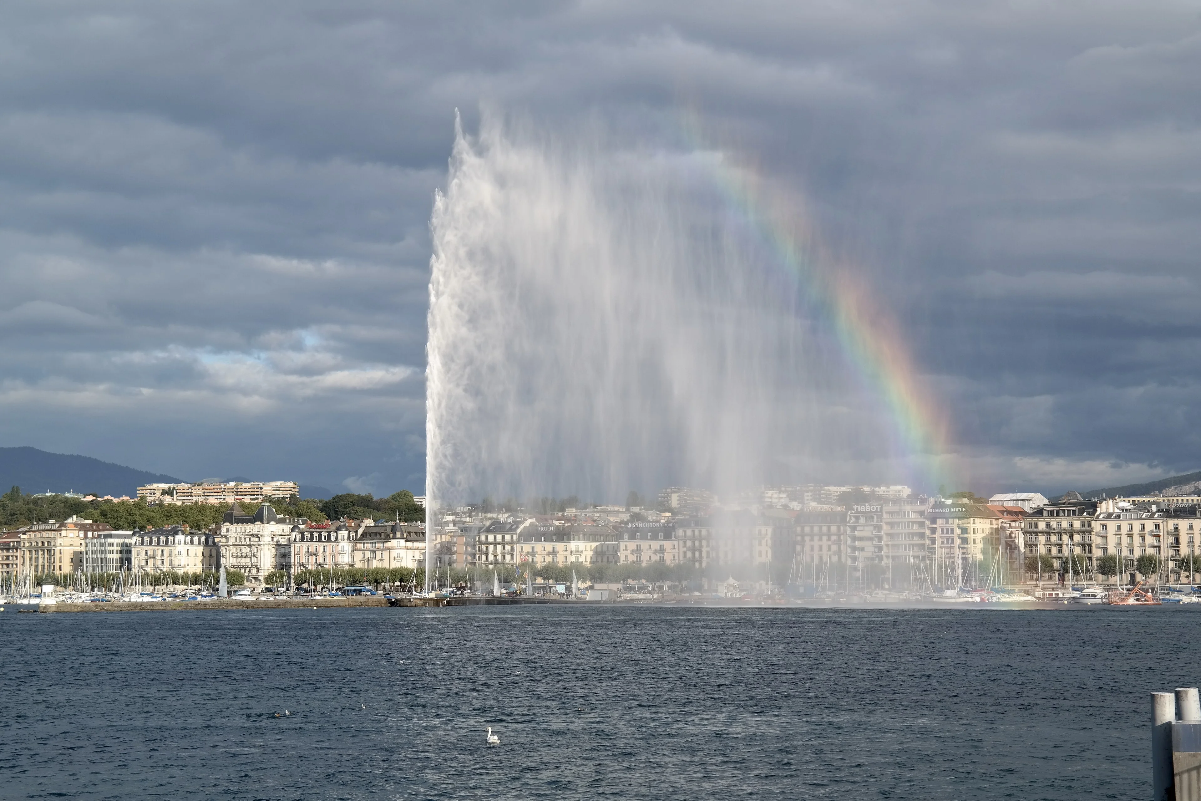 The Jet d'Eau fountain on Lake Geneva with a rainbow over the city waterfront