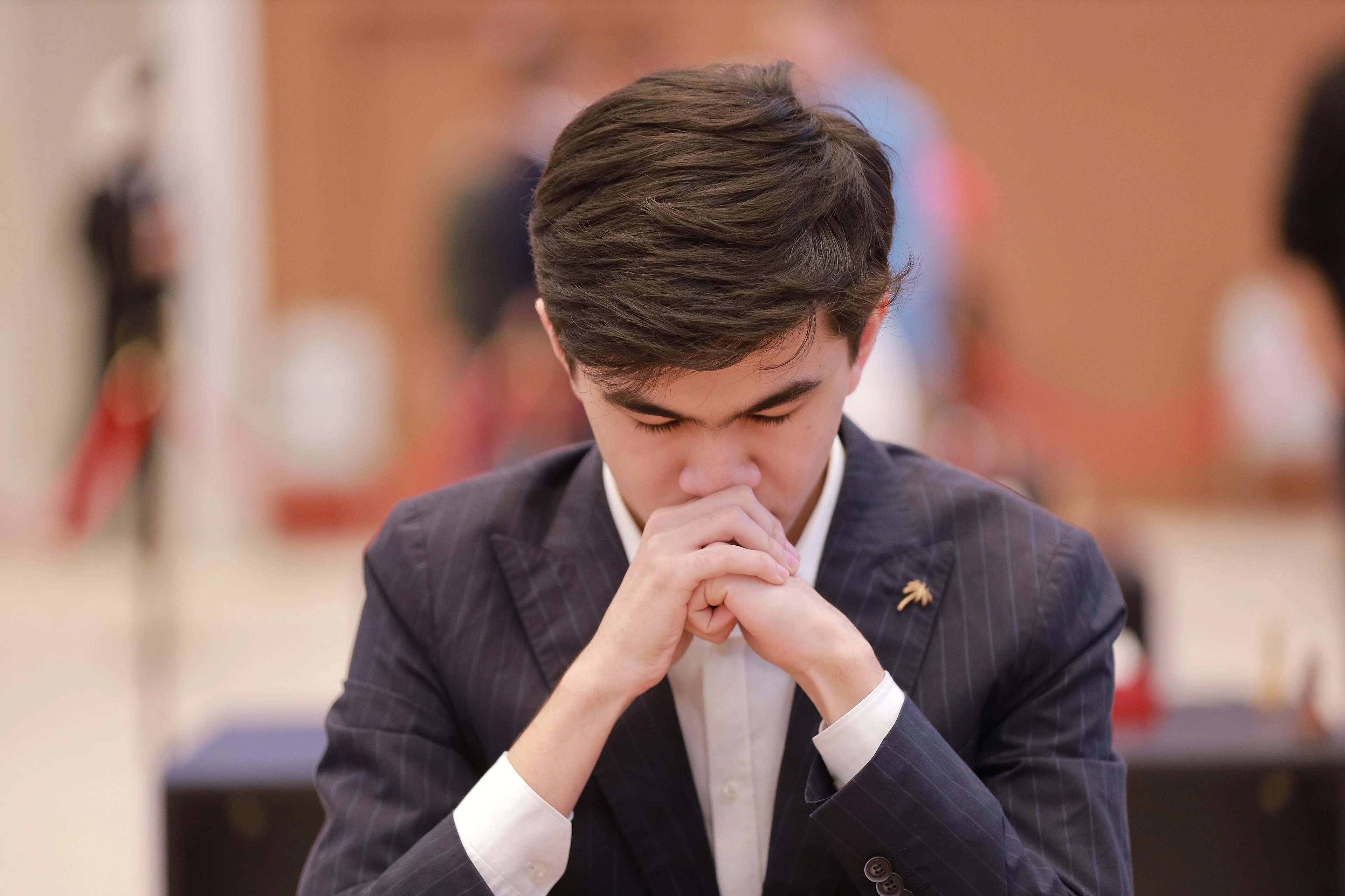 Javokhir Sindarov thinking with his hands clasped in front of his face during a tournament game